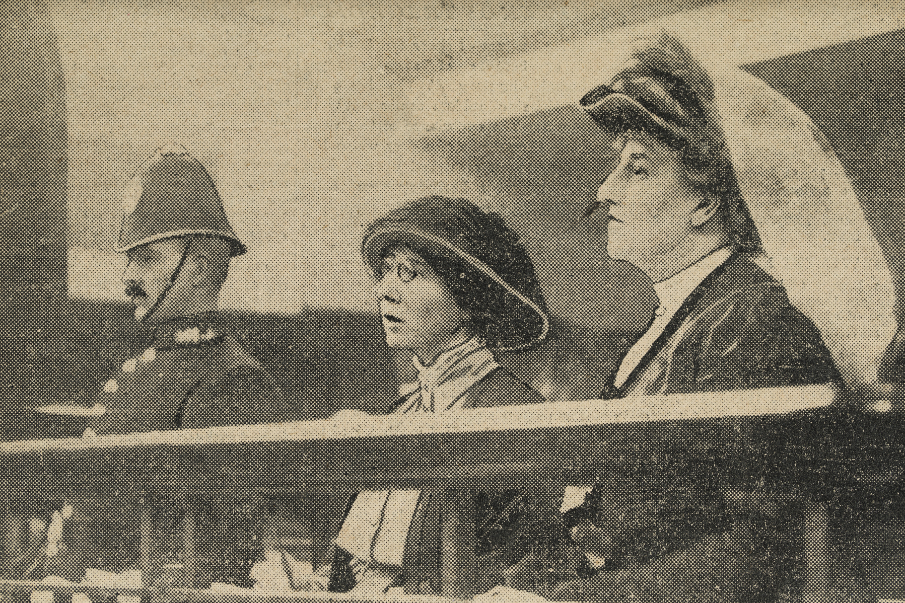 Photograph of Ethel Moorhead and Dorothea Smith in court. At the far left is a policeman, in the middle is Moorhead and at the far right is Smith.