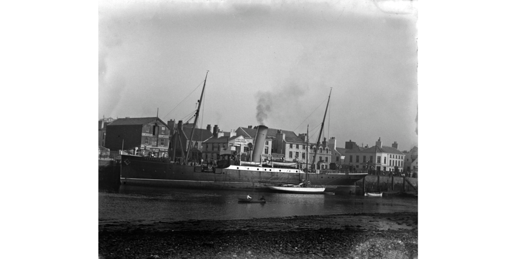 Black and white photo of a ship alongside a quay. This is the tender 'Hesperus'
