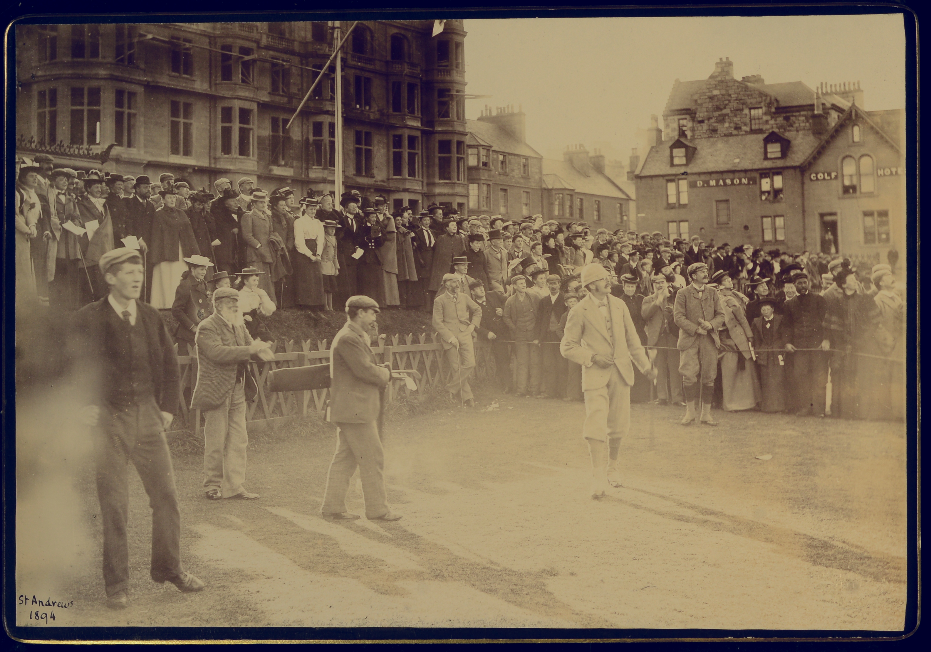 Arthur James Balfour on a St Andrews golf course driving himself into office as Captain of the Royal and Ancient Golf Club St Andrews. Surrounded by a large ground of spectators.