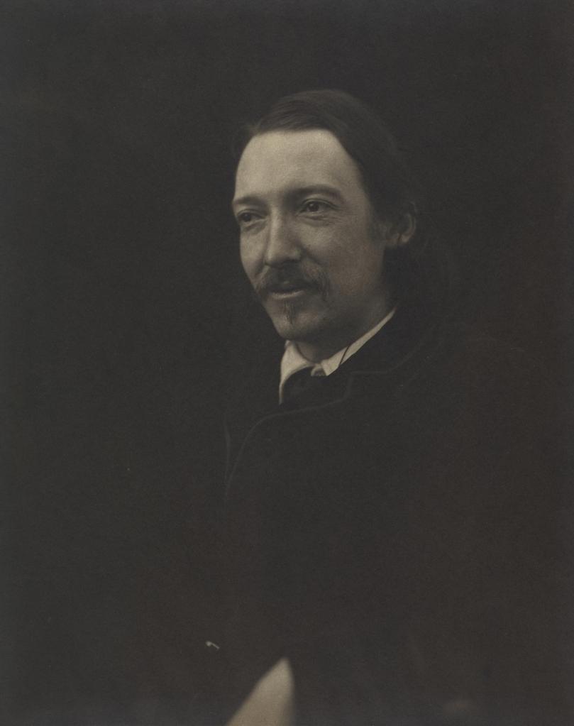A sepia-toned portrait of a man with long hair and a mustache, wearing a dark coat, against a dark background.